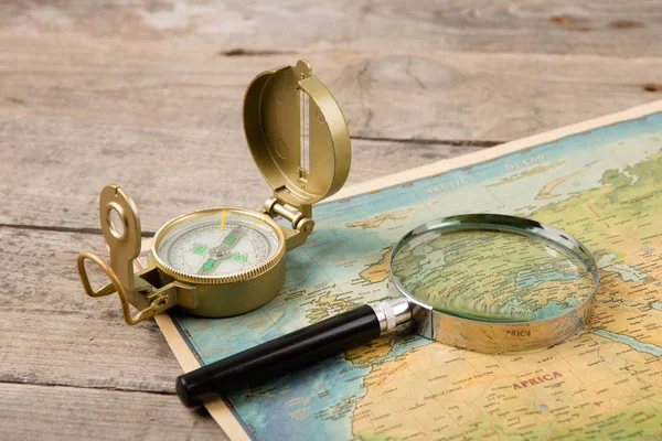 木制桌子上的指南针和老式地图 — 图库照片