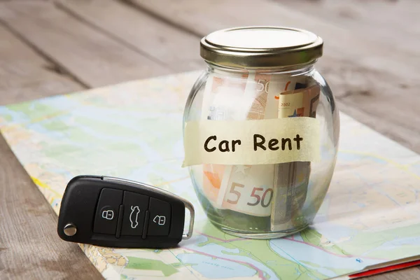 Car rent concept - money glass , car key and roadmap
