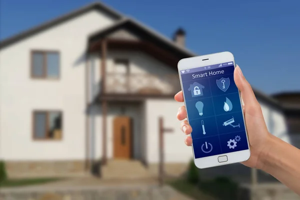 Binanın arka planında ev güvenliği uygulaması olan akıllı telefon.