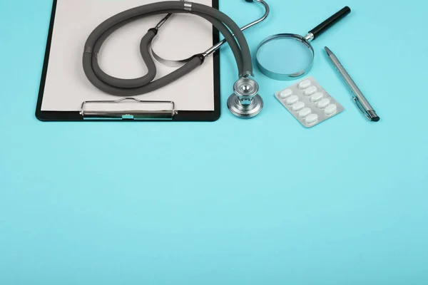 Lugar de trabajo médicos - tableta médica, estetoscopio, pastillas y lupa Imagen de stock