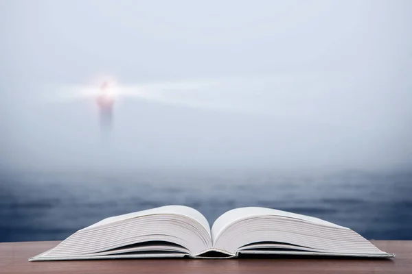 Concepto de sabiduría - libro abierto sobre el mar y el fondo del faro Imagen de stock