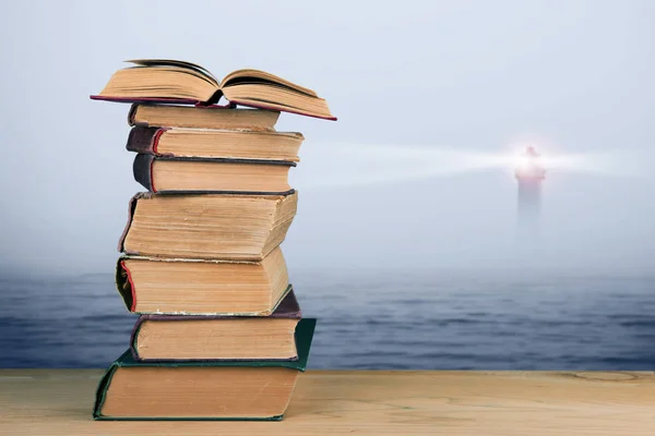 Wijsheid concept - stapel boeken over zee en de vuurtoren achtergrond — Stockfoto
