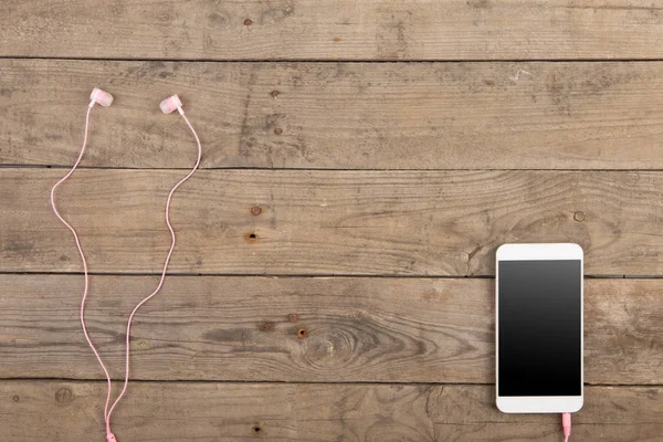 Smartphone blanco con auriculares en el tablero de madera viejo —  Fotos de Stock