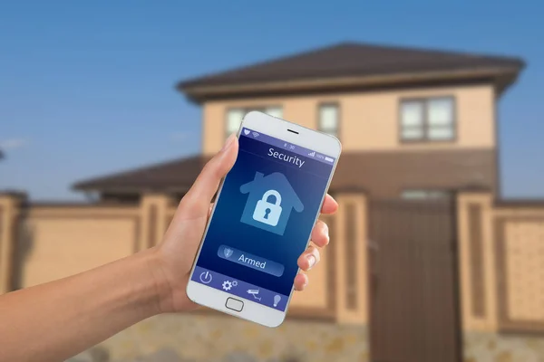 Smartfon z domową aplikacją bezpieczeństwa w dłoni na tle budynku — Zdjęcie stockowe
