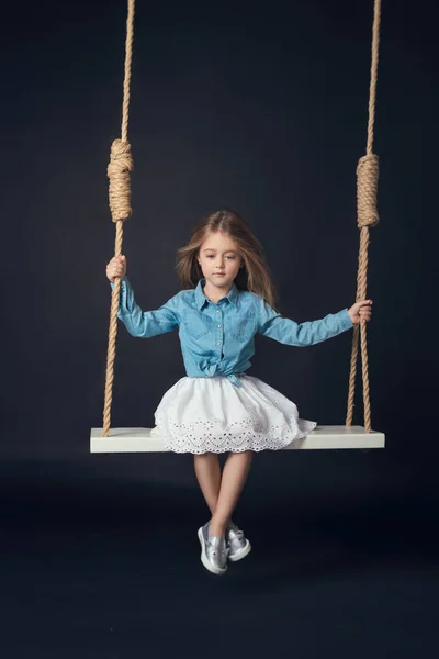 Μικρό κορίτσι σε μια κούνια σε ένα σακάκι τζιν — Φωτογραφία Αρχείου