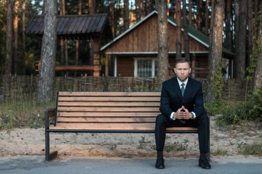 bir bankta oturan iş elbiseli bir adam