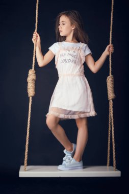 küçük kız bir salıncak üzerinde stüdyoda poz