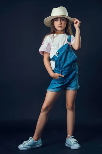 Küçük kız kot tulum ve Studio hasır şapka — Stok fotoğraf