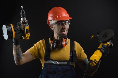 Genç bir adam bir siyah arka plan çalışma üniforma ve İnşaat Aracı poz