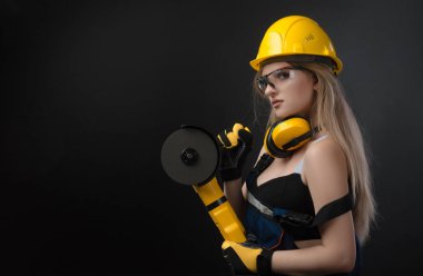 siyah arka plan üzerinde açı öğütücü ile sert bir şapka kadın inşaat işçisi