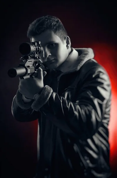 Hombres jóvenes con armas posando sobre un fondo negro en retroiluminación —  Fotos de Stock