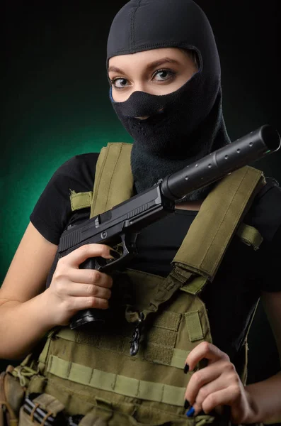 La chica con ropa militar especial posando con un arma en sus manos sobre un fondo oscuro en la niebla —  Fotos de Stock