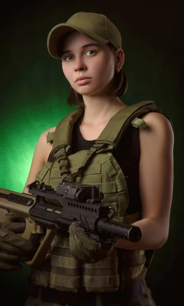 ヘイズの暗い背景の上に手で銃を持つポーズ軍の特別な服の女の子 — ストック写真