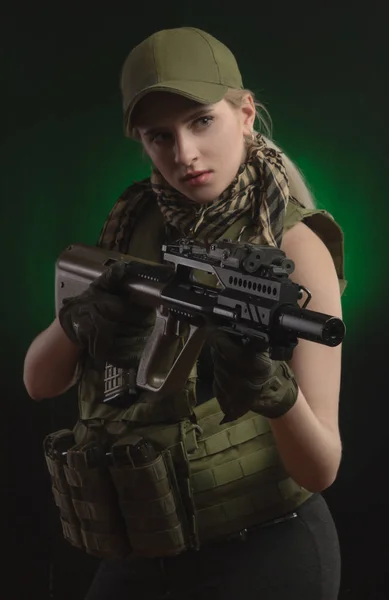 La chica con ropa militar especial posando con un arma en sus manos sobre un fondo oscuro en la niebla — Foto de Stock