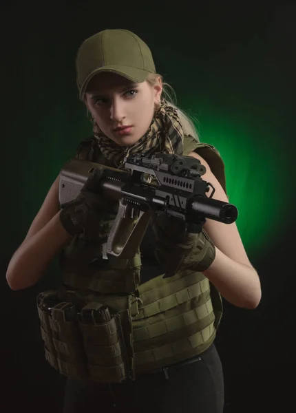 The girl in military special clothes posing with a gun in his hands on a dark background in the haze — Stock Photo, Image