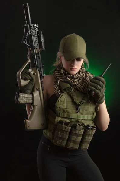 Das Mädchen in militärischer Spezialkleidung posiert mit einem Gewehr in der Hand vor dunklem Hintergrund im Dunst — Stockfoto
