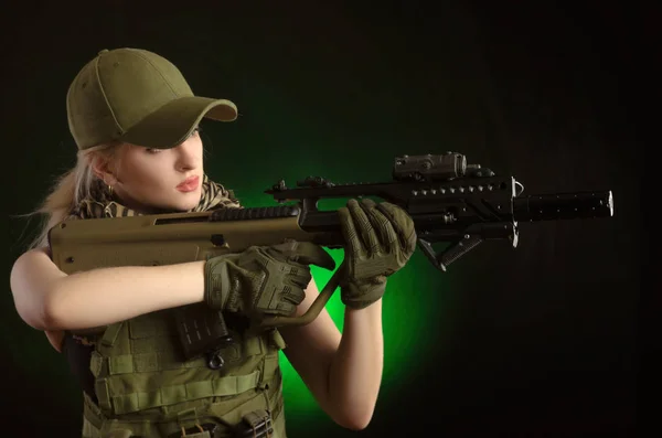 Dziewczyna w wojskowych specjalne ubrania pozowanie z bronią w ręku na ciemnym tle w haze — Zdjęcie stockowe