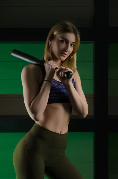 Deportivo delgado chica posando en gimnasio con acero pesado béisbol bat — Foto de Stock