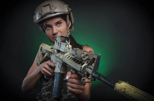 La chica con ropa militar especial posando con un arma en sus manos sobre un fondo oscuro en la niebla —  Fotos de Stock