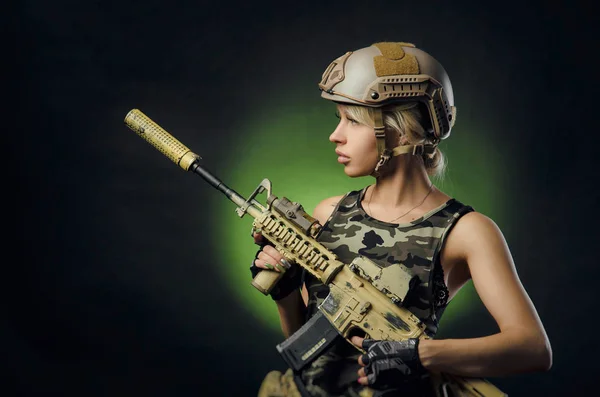 Het meisje in militaire overalls Airsoft poseren met een pistool in zijn handen op een donkere achtergrond in de Haze — Stockfoto