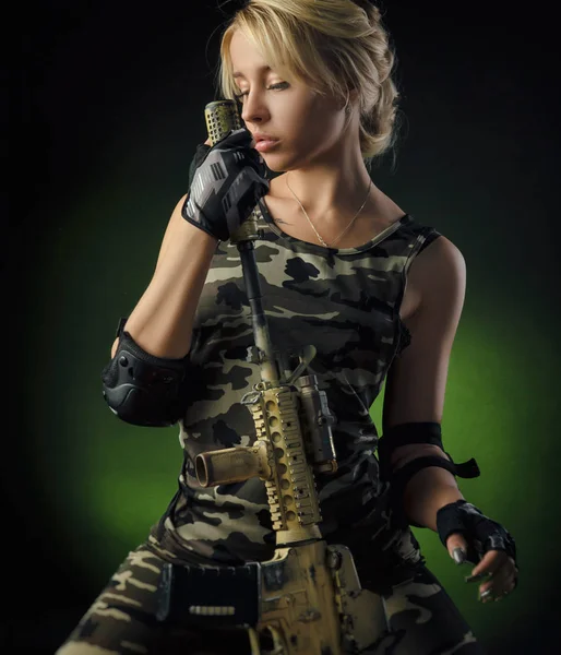 the girl in military special clothes posing with a gun in his hands on a dark background in the haze