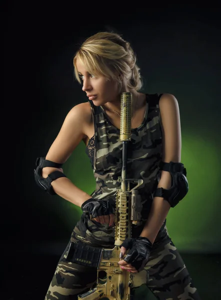 Het meisje in militaire speciale kleren poseren met een pistool in zijn handen op een donkere achtergrond in de nevel — Stockfoto