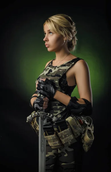 La chica en mono militar airsoft posando con una pistola en sus manos sobre un fondo oscuro en la niebla —  Fotos de Stock