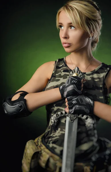 A menina em macacão militar airsoft posando com uma arma em suas mãos em um fundo escuro na névoa — Fotografia de Stock