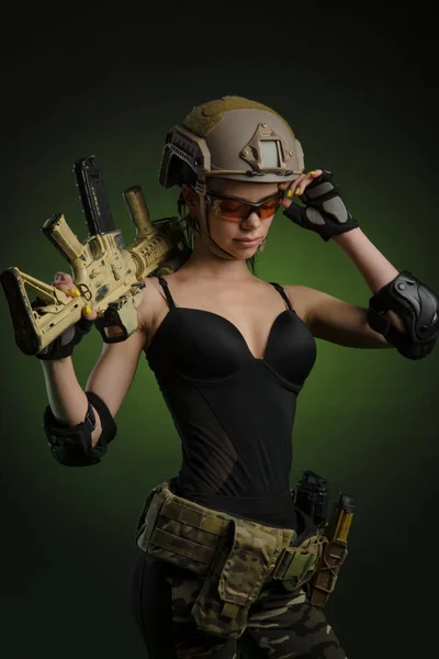 Dívka v vojenské speciální oblečení pózuje s pistolí v ruce na tmavém pozadí v oparu — Stock fotografie