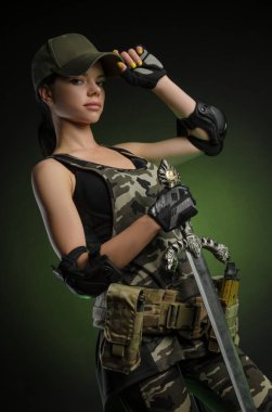 sevdanın karanlık bir arka plan üzerinde elinde bir silahla poz askeri özel giysili kızı