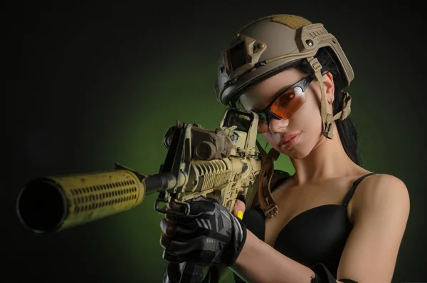 The girl in military special clothes posing with a gun in his hands on a dark background in the haze — Stock Photo, Image