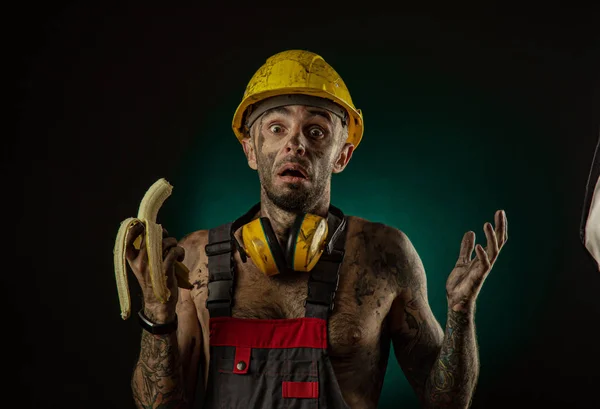 Portret van een gelukkig lachende mijnwerker het eten van een banaan voor de lunch Stockfoto