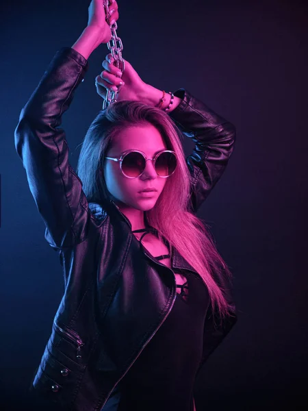 Hermosa chica con estilo de moda en traje de cuerpo posando en el estudio de la foto sobre fondo oscuro con cadenas en luz de neón — Foto de Stock