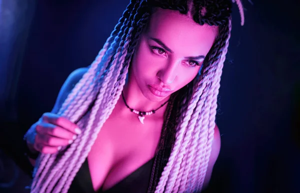 Bela menina sexy com longos dreadlocks posando em luz de néon — Fotografia de Stock