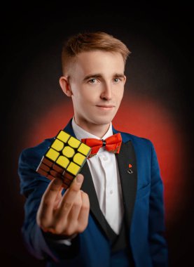 Genç bir çocuk - sihirbaz illüzyonisti bir Rubiks küpü gösteriyor