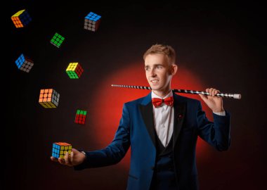 Genç bir çocuk - sihirbaz illüzyonisti bir Rubiks küpü gösteriyor