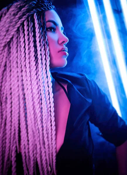 Красива сексуальна дівчина з довгими дредлоками позує в неоновому світлі — стокове фото