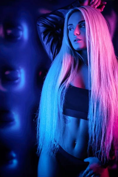Hermosa chica con estilo de moda en traje de cuerpo posando en el estudio de la foto sobre fondo oscuro en luz de neón — Foto de Stock