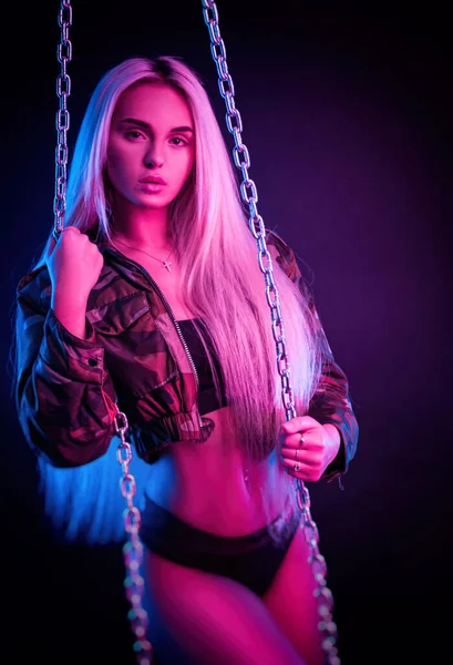 Piękne stylowe modne dziewczyny w Body stwarzające w Photo Studio na ciemnym tle z łańcuchami w świetle Neon — Zdjęcie stockowe