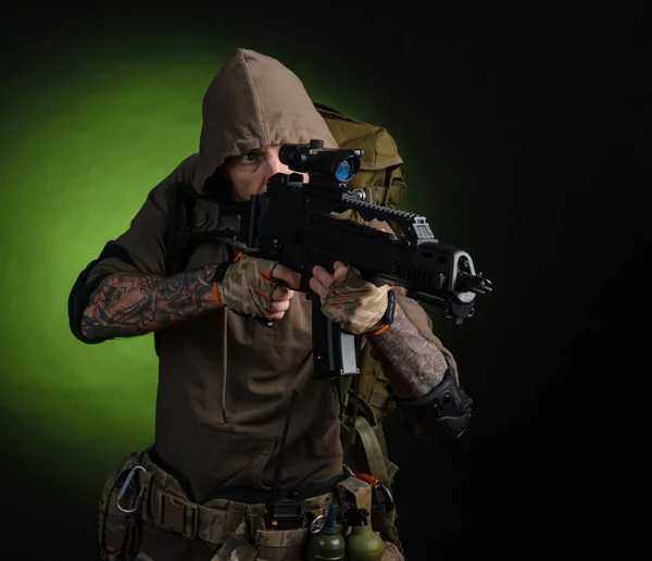 Man Stalker med en pistol med en optisk syn och en ryggsäck på en mörk bakgrund — Stockfoto
