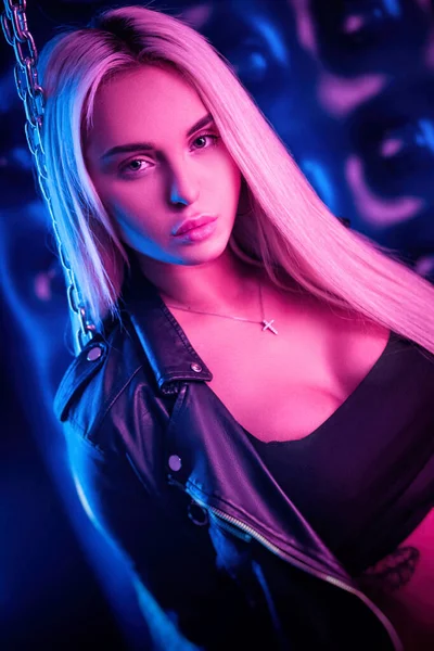 Beautiful stylish fashionable girl in bodysuit posing in photo Studio on dark background with chains in neon light — Stock Photo, Image