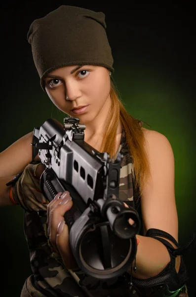 La chica en mono militar airsoft posando con una pistola en sus manos sobre un fondo oscuro en la niebla — Foto de Stock