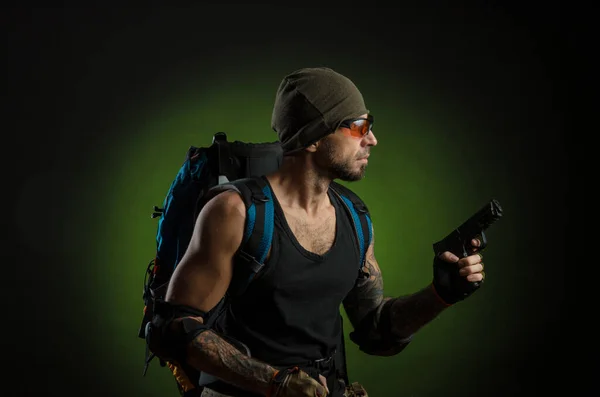man with gun and backpack on dark background