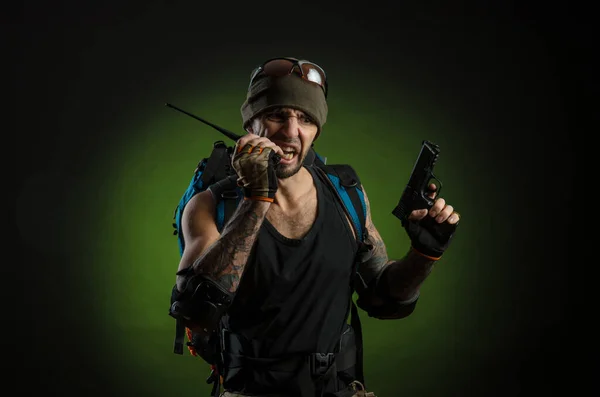 Mężczyzna z bronią i plecakiem na ciemnym tle — Zdjęcie stockowe