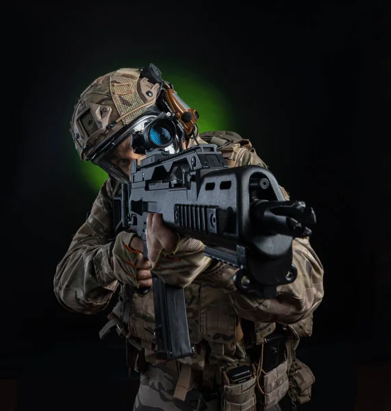 Un soldado en ropa militar con un arma sobre un fondo oscuro —  Fotos de Stock