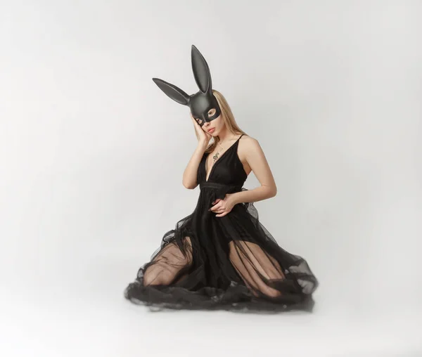 Beautiful blonde in a rabbit mask in a sexy evening dress on a white background — Stock Photo, Image