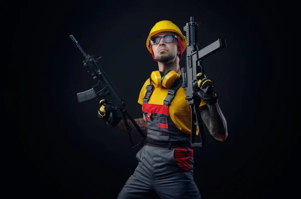 Un homme en uniforme d'ouvrier de la construction portant un casque avec une arme airsoft dans les mains — Photo