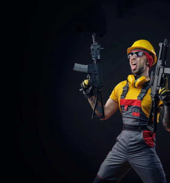 Mężczyzna w mundurze robotnika budowlanego noszący twardy kapelusz z airsoftową bronią w rękach — Zdjęcie stockowe