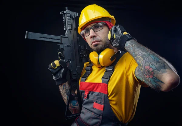 Un homme en uniforme d'ouvrier de la construction portant un casque avec une arme airsoft dans les mains — Photo