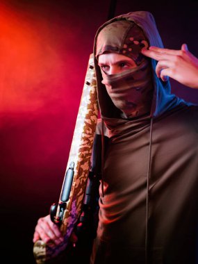 Neon ışığında keskin nişancı tüfeği olan kar maskeli bir adam.